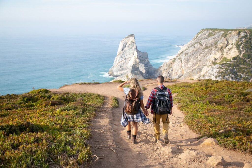 A couple hiking at Cabo da Roca, Portugal with stunning coastline views during the day.