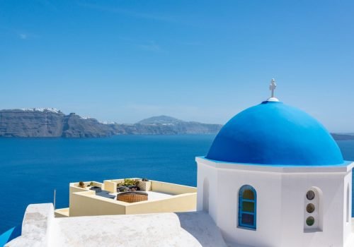 Iconic blue dome church in Santorini with a stunning view of the Aegean Sea.